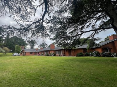 Fabulosa casa distribuida en una única planta. El parque tiene 110m de frente a la cancha de Golf.
Ingreso principal por hall. A la derecha se encuentra el área social y a su izquierda el área de .dormitorios.
Derecha: se encuentra el living comedor con techos altos, amplios ventanales, estufa a leña, barra revestida de cedro.
Antecocina y cocina de grandes dimensiones. Lavadero. Garaje para dos autos.
Dos dependencias de servicio, cada una con su propio baño.
Área de huéspedes con un living, estar y dormitorio.
Izquierda: 3 dormitorios dos de ellos en suite, 3 baños en total. Suite principal con estufa a leña y salida al exterior a terrazas con magníficas vistas.
Gran parque con arboles de muchos años, cuenta con piscina, estanqué y parrillero.
La casa esta en funcionamiento. Construida con excelentes materias, pisos de madera, piedra laja, muros de ladrillo, aberturas y todos los detalles en madera son de cedro. Ideal para actualizarla
BINTANG Propiedades

